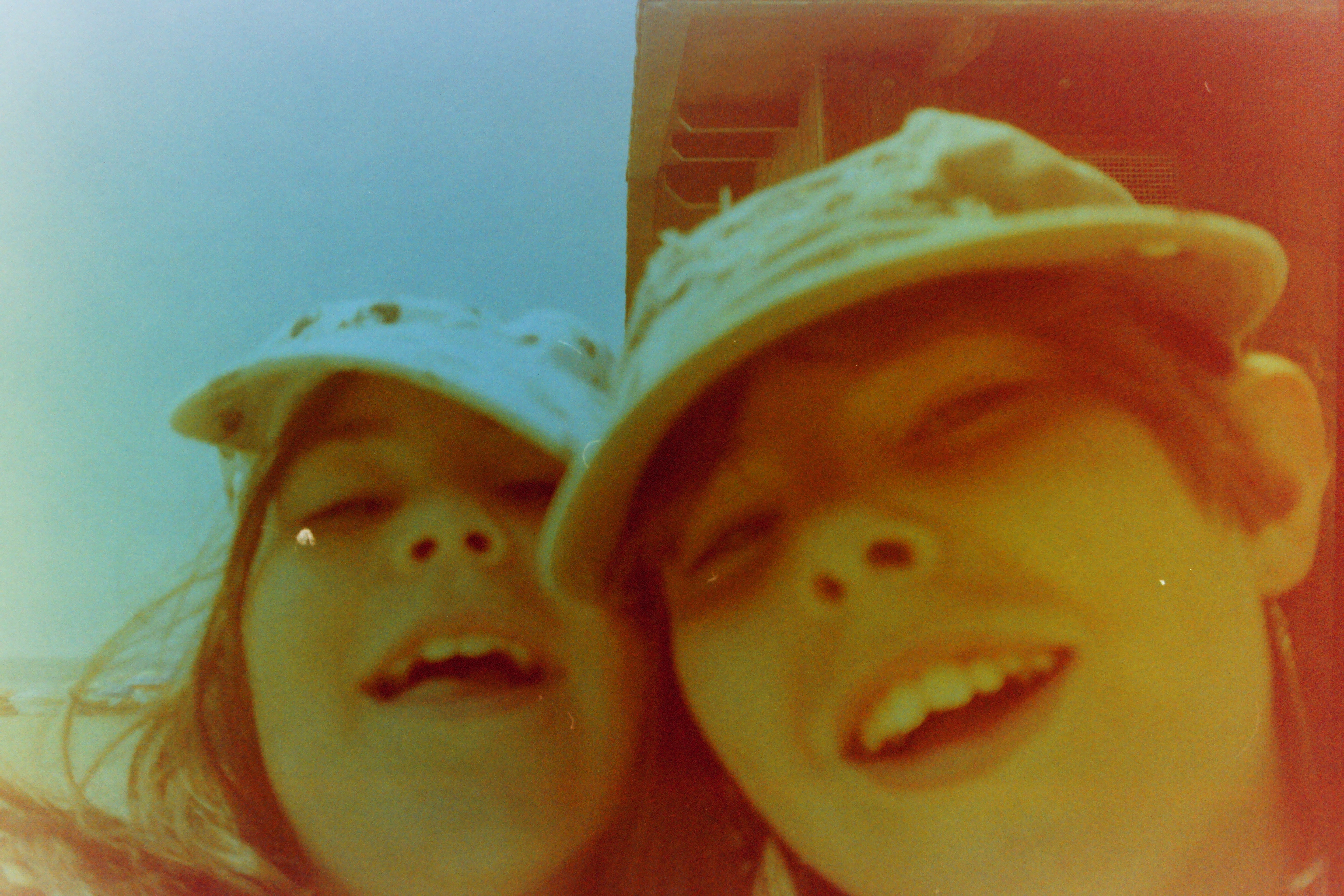 Dos niñas con gorra fotografiadas de cerca en un carrete caducado