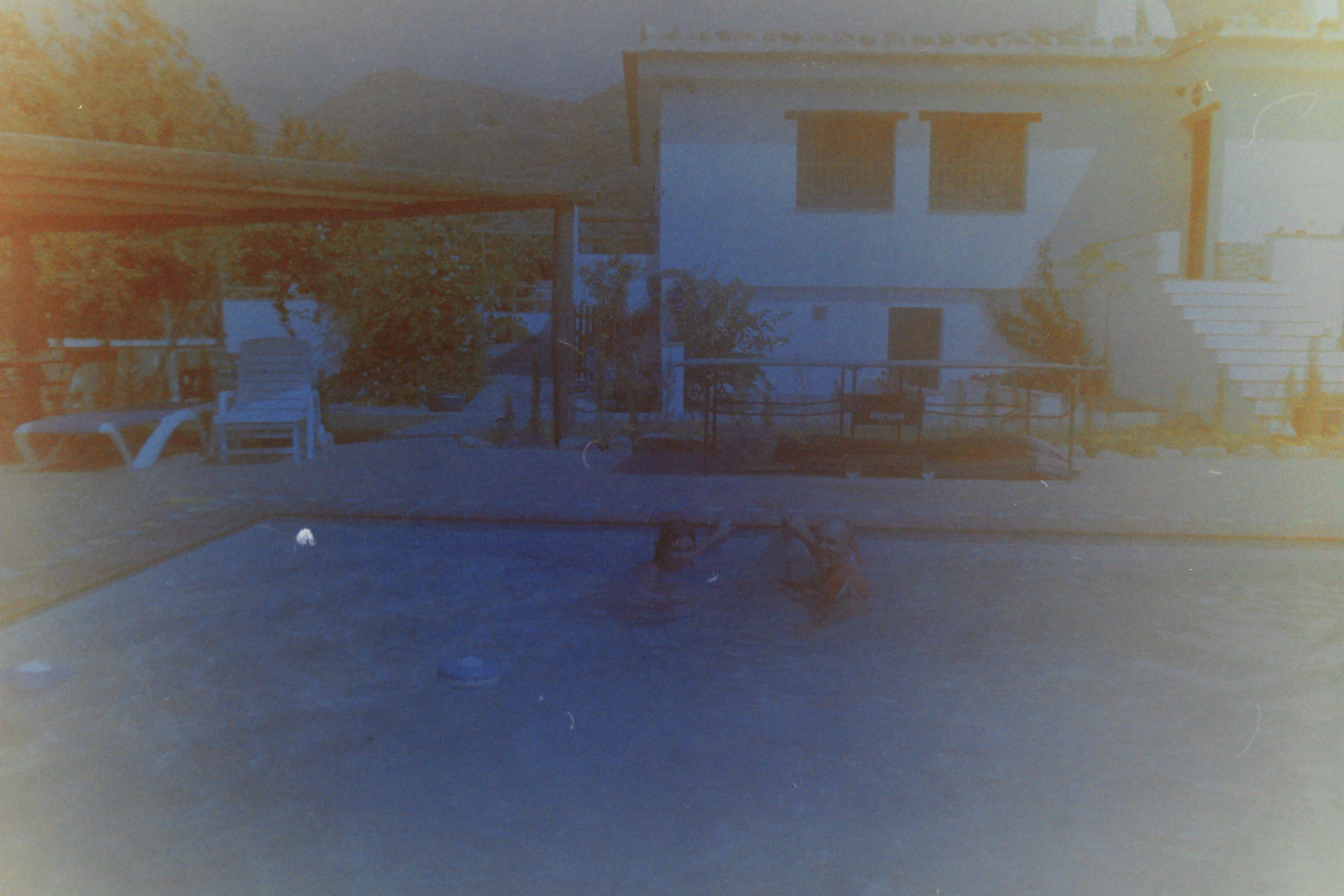 Vista de una piscina y una casa fotografiadas en un carrete caducado